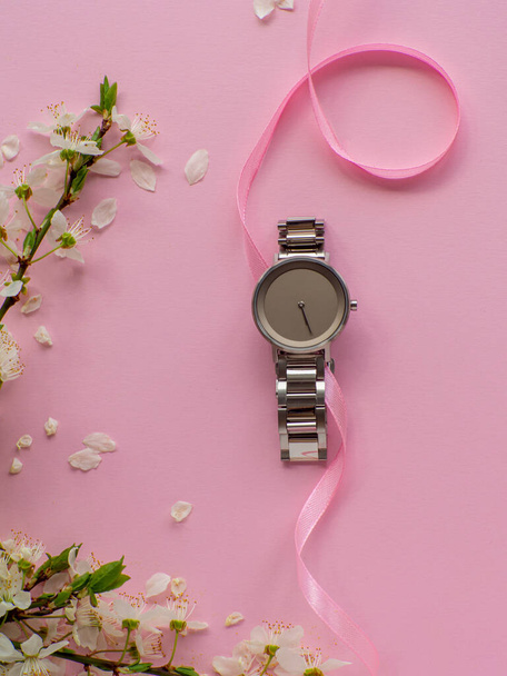 Womens hand watch on pink background with cherry flowers and copy space. Womens, Valentines and Mothers Day gift. Concept of beauty, elegance and femininity. Buying birthday gifts online. - Fotoğraf, Görsel