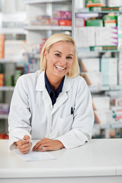 I help people achieve the best results from their medication. Portrait of a pharmacist working in a drugstore. All products have been altered to be void of copyright infringements - Foto, Imagem