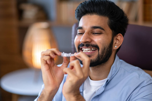 Happy man putting clear invisible dental aligners in his mouth to straighten his curves teeth - 写真・画像