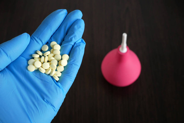 mains tenant des pilules sur lavement sur fond en bois, lavement vs pilules pour le traitement de la constipation intestinale concept - Photo, image