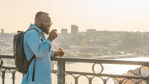 Молодий афроамериканець з кавою на мосту Дом Луїс, який дивиться на місто Порту. Подорож по Португалії - Фото, зображення