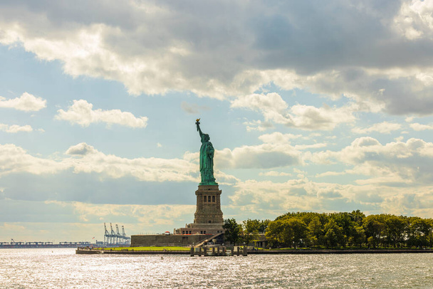 Όμορφη θέα του αγάλματος της ελευθερίας στο νησί της ελευθερίας στη Νέα Υόρκη στο δέλτα του ποταμού Hudson στον ουρανό με φόντο σύννεφα. ΗΠΑ. - Φωτογραφία, εικόνα