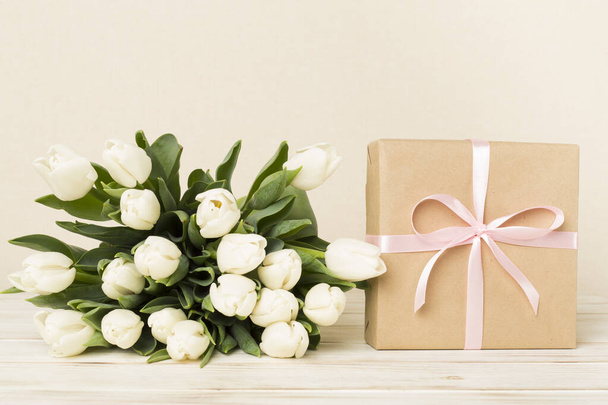 White tulip bouquet with gift box on table - Fotoğraf, Görsel