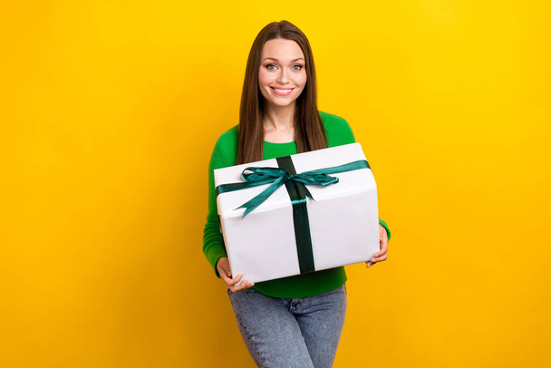 Photo of shiny adorable woman wear green sweater holding big present box isolated yellow color background. - Foto, immagini