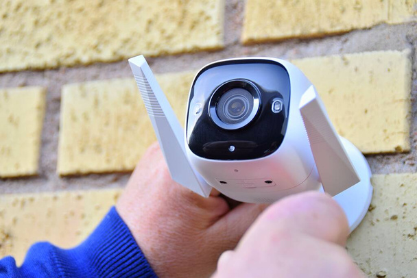Surveillance camera in male. Installing a CCTV camera for home security.  - 写真・画像