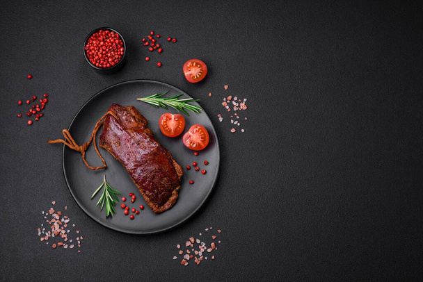 Delicious duck fillet or breast grilled or smoked with spices and salt on a dark concrete background - 写真・画像