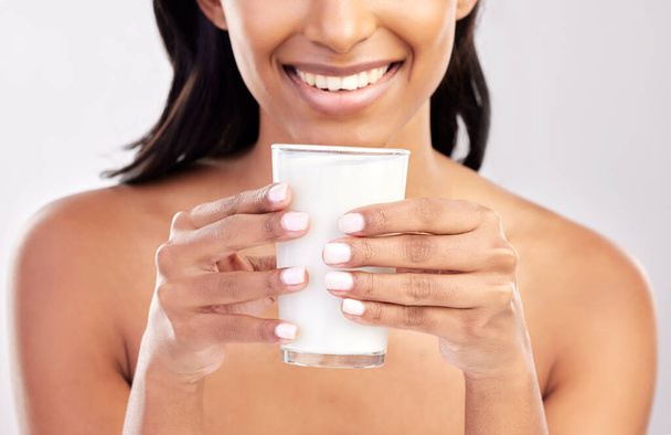 Woman with smile, glass of milk in hands and health with nutrition, vitamins and calcium on studio background. Organic, healthy lifestyle and wellness with happy female, diet and dairy product. - Photo, Image