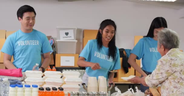 волонтеры в синих футболках кормят нуждающихся - Кадры, видео