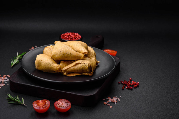 Delicious pancakes triangular shape with meat, salt and spices on a dark concrete background - Photo, Image