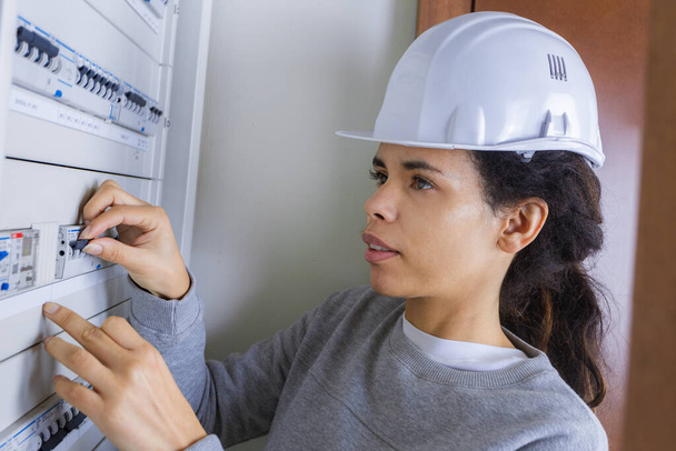 young female electrician adjusting circuit breaker fuse - Foto, afbeelding