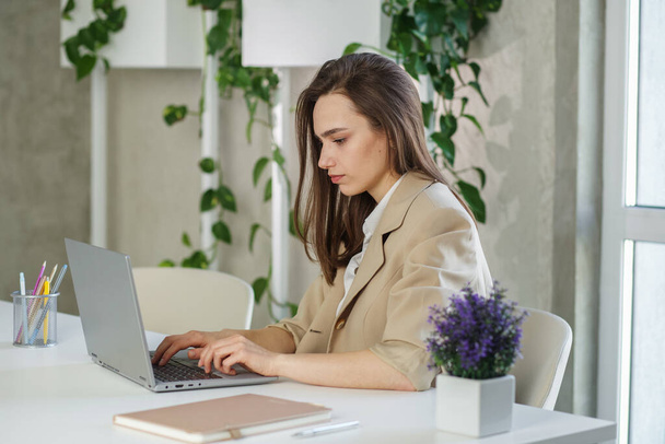 Kobieta pracuje na laptopie w nowoczesnym biurze. Wykonywanie analizy księgowej sprawozdania z inwestycji w nieruchomości, koncepcja systemów finansowych i podatkowych - Zdjęcie, obraz