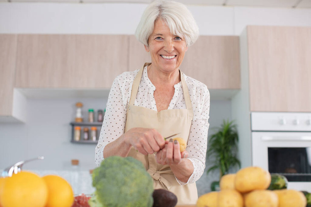 portrait of a grandmother cutting veggies - Foto, afbeelding