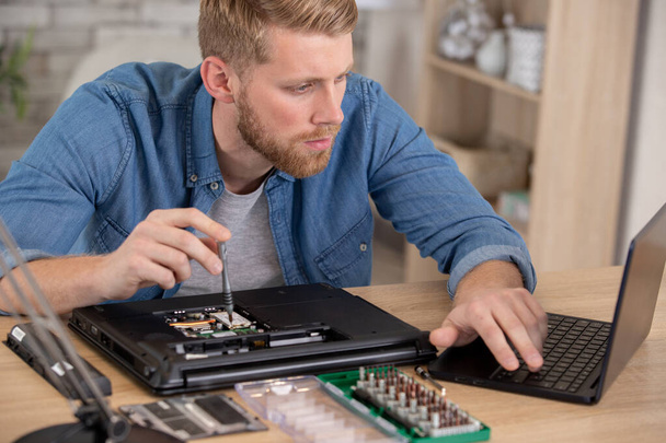 man repair laptop motherboard with screwdriver white coat - Fotó, kép