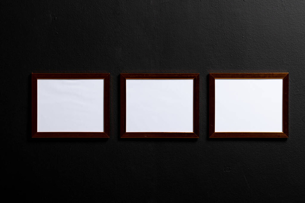 Brown empty frames with copy space on black wall. Mock up frame template, interior design and decoration. - Foto, Bild