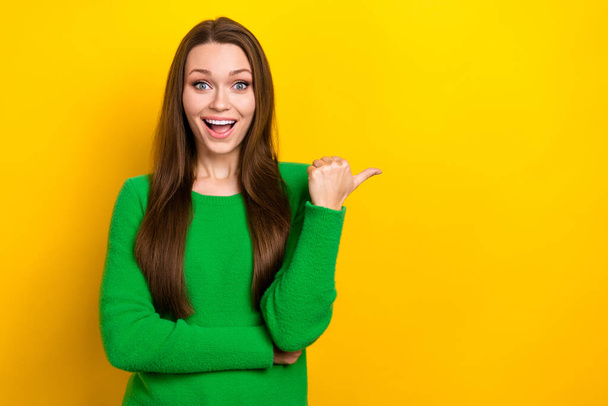 Photo of funny excited woman wear green sweater pointing thumb emtpy space isolated yellow color background. - Fotó, kép