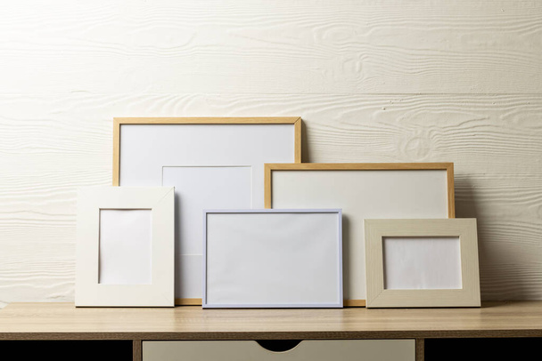 Colourful empty frames with copy space on table against white wall. Mock up frame template, interior design and decoration. - Foto, imagen