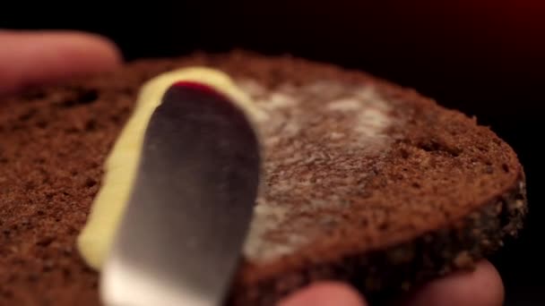 statische macro schoot de hand van de vrouw met een schijfje roggebrood, en verspreidde de boter erop - Video