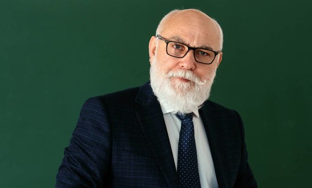 Elderly teacher. Funny professor or scientist in a elegant suit. Copy space on chalkboard, blackboard, banner - Valokuva, kuva