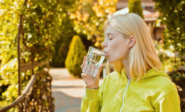 Mujer joven bebiendo agua en el parque de otoño. Estilo de vida activo en otoño día soleado al aire libre. Chica usando suéter brillante en increíbles hojas otoñales de fondo
 - Foto, Imagen