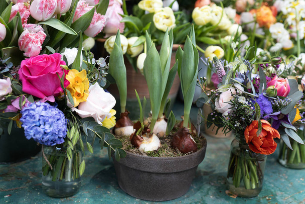 Bouquet de mariée modeste de printemps avec rose rouge, eucalyptus, tulipe, ranunculus dans un bocal en verre sur une table en fer - Photo, image