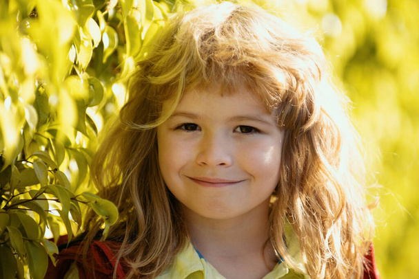 Happy smiling child, adorable lovely kid. Joyful portrait of small child on green nature background outside - Foto, imagen