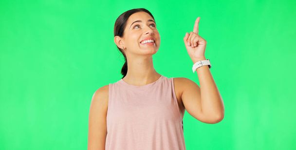 Woman face, pointing up and green screen with happiness and smile showing mockup for advertisement. Portrait, isolated and studio background with a happy young female point to show promotion deal. - Fotó, kép