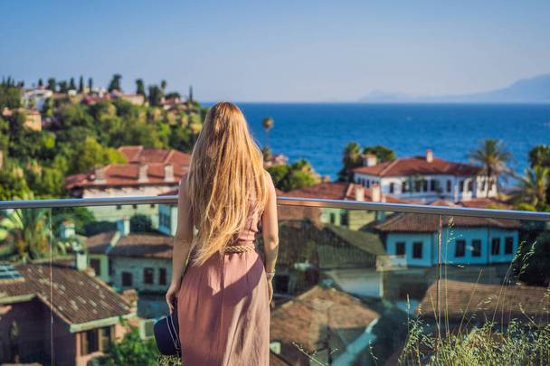 Woman tourist in Old town Kaleici in Antalya. Turkiye. Panoramic view of Antalya Old Town port, Taurus mountains and Mediterrranean Sea, Turkey. - Photo, image