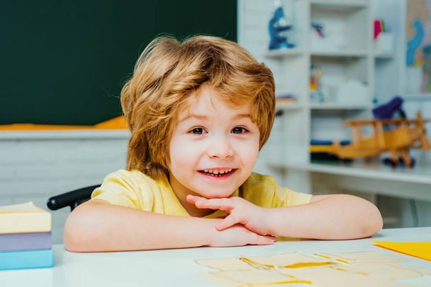Cute little preschool kid boy with teacher study in a classroom - Фото, зображення
