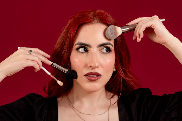 Close up of atylish woman holding make-up brushes while posing against an isolated background. Beauty and cosmetic concept. - Φωτογραφία, εικόνα