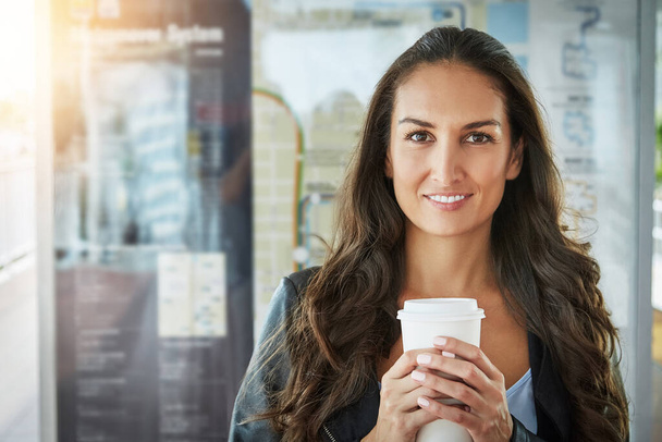 Genieten van haar koffie om mee te nemen. Portret van een jonge vrouw met een kop koffie in een stedelijke omgeving - Foto, afbeelding
