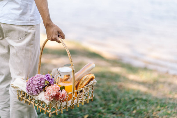 Couple walking in garden with picnic basket. in love couple is enjoying picnic time in park outdoor - Fotoğraf, Görsel