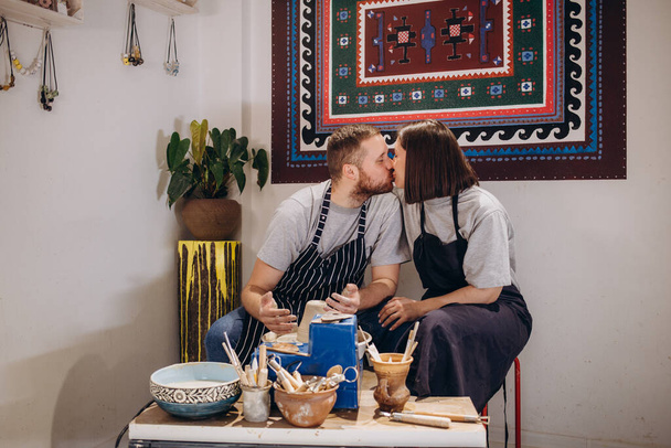 Couple in love working together on potter wheel in craft studio workshop. - Foto, Imagen