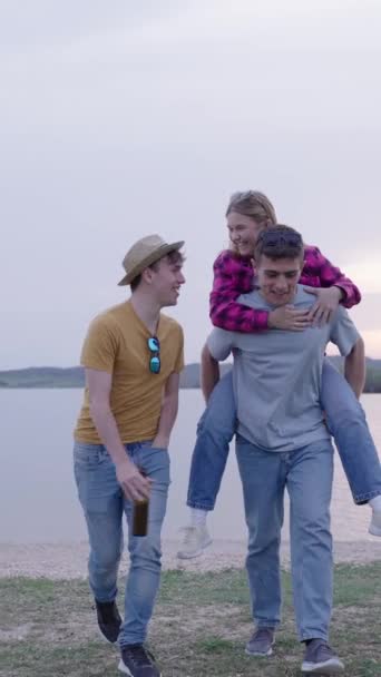 Eine Gruppe junger Freunde vergnügt sich draußen in der Natur. Menschen gehen am See entlang - Filmmaterial, Video