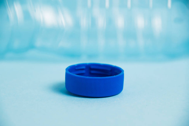 Macro plastic cap and blue bottle on paper background. Concept of earth day, zero waste and plastic recycling - Foto, Imagem