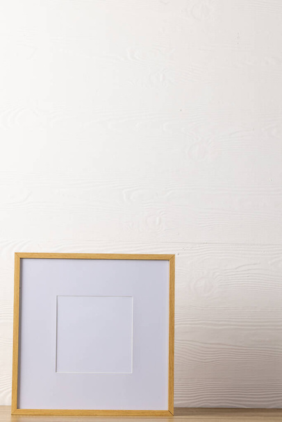 Vertical of empty wooden frame with copy space on table against white wall. Mock up frame template, interior design and decoration. - Foto, imagen