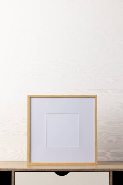 Vertical of empty wooden frame with copy space on table against white wall. Mock up frame template, interior design and decoration. - Foto, imagen
