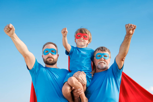 Senior, man and child outdoor against summer blue sky. Grandfather, father and son pretend to be superheroes. People having fun together. Family holiday concept. Happy Father's day - Photo, image