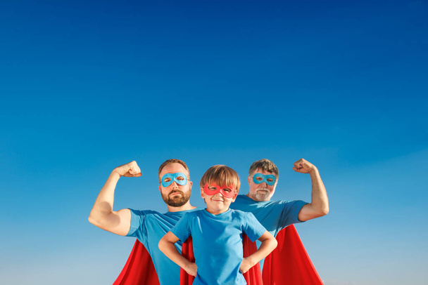 Senior, man and child outdoor against summer blue sky. Grandfather, father and son pretend to be superheroes. People having fun together. Family holiday concept. Happy Father's day - Photo, image