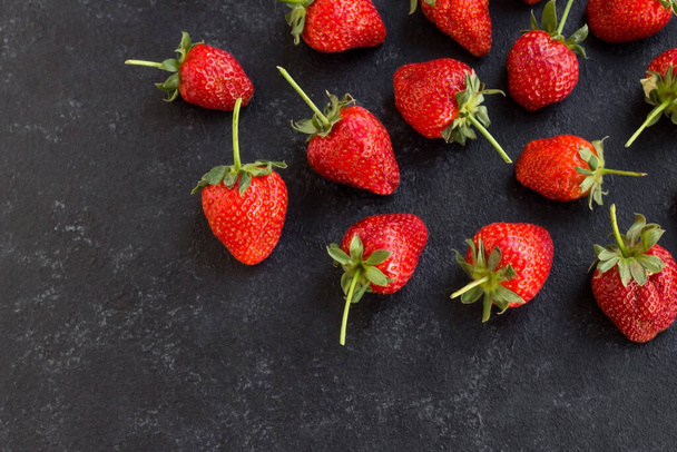 New harvest, fresh whole red strawberries, designed in black textured surface - 写真・画像