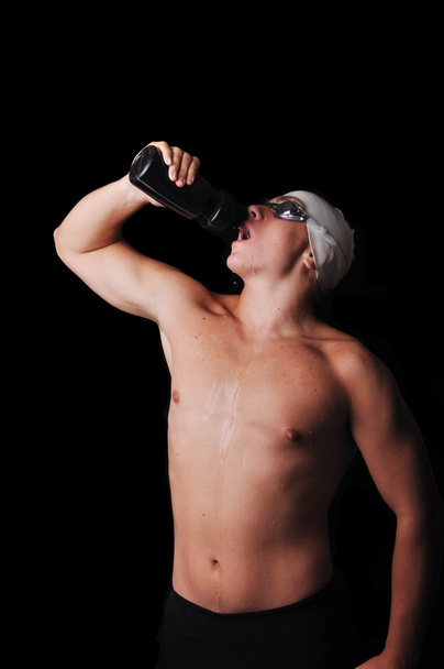 Male swimmer drinking water isolated in black - Fotografie, Obrázek