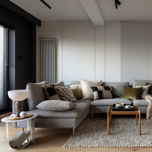 Creative composition of living room interior with design gray sofa, wooden coffee table, stylish carpet, beige side table, pillows, personal accessories and big tv. Stylish home decor. Template. - 写真・画像