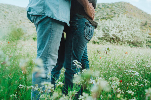 Atividade de lazer ao ar livre romântico e casal apaixonado abraçando e beijando no meio de flores de primavera verde prado. Pessoas apreciando a natureza e romance relacionamento juntos. Férias. - Foto, Imagem
