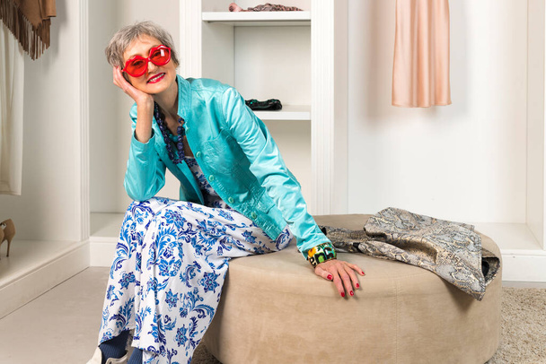 Una anciana elegante está sentada en un vestidor y armario. Concepto de Envejecimiento y Belleza. - Foto, imagen
