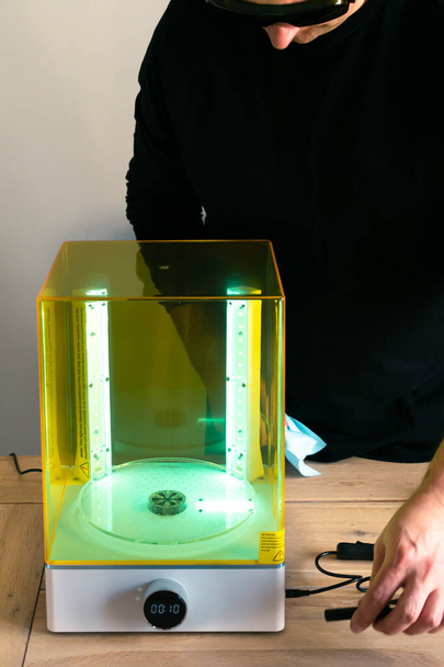 Uomo che indossa occhiali che regolano una lavatrice e curano la macchina utilizzando la luce UV prima dell'uso, per stampante in resina 3d - Foto, immagini