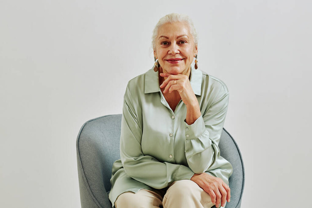 Minimal portrait of elegant senior woman looking at camera and smiling while posing in studio, copy space - Photo, Image