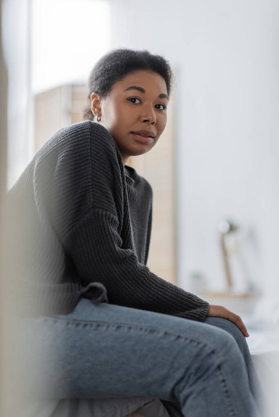 Stressed multiracial woman with mental problem looking at camera in blurred bedroom at home  - Foto, Bild
