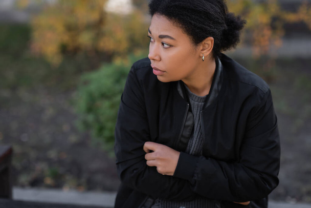 Jeune femme multiraciale avec dépression assise à l'extérieur en automne  - Photo, image