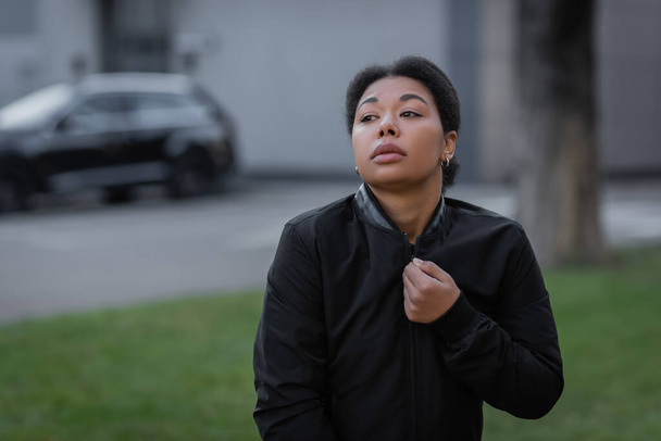 multiracial woman with psychological problem wearing jacket on urban street  - Фото, зображення
