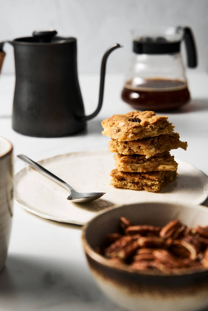 galletas blondie cuadrados en plato blanco. Composición de desayuno dulce con café y galletas rubias. Foto de alta calidad - Foto, imagen