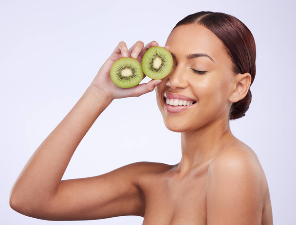 Happy, skincare and kiwi with woman in studio for natural cosmetics, diet and nutrition. Product, glow and self care with female model and fruit on white background for spa, food and vitamin. - Zdjęcie, obraz